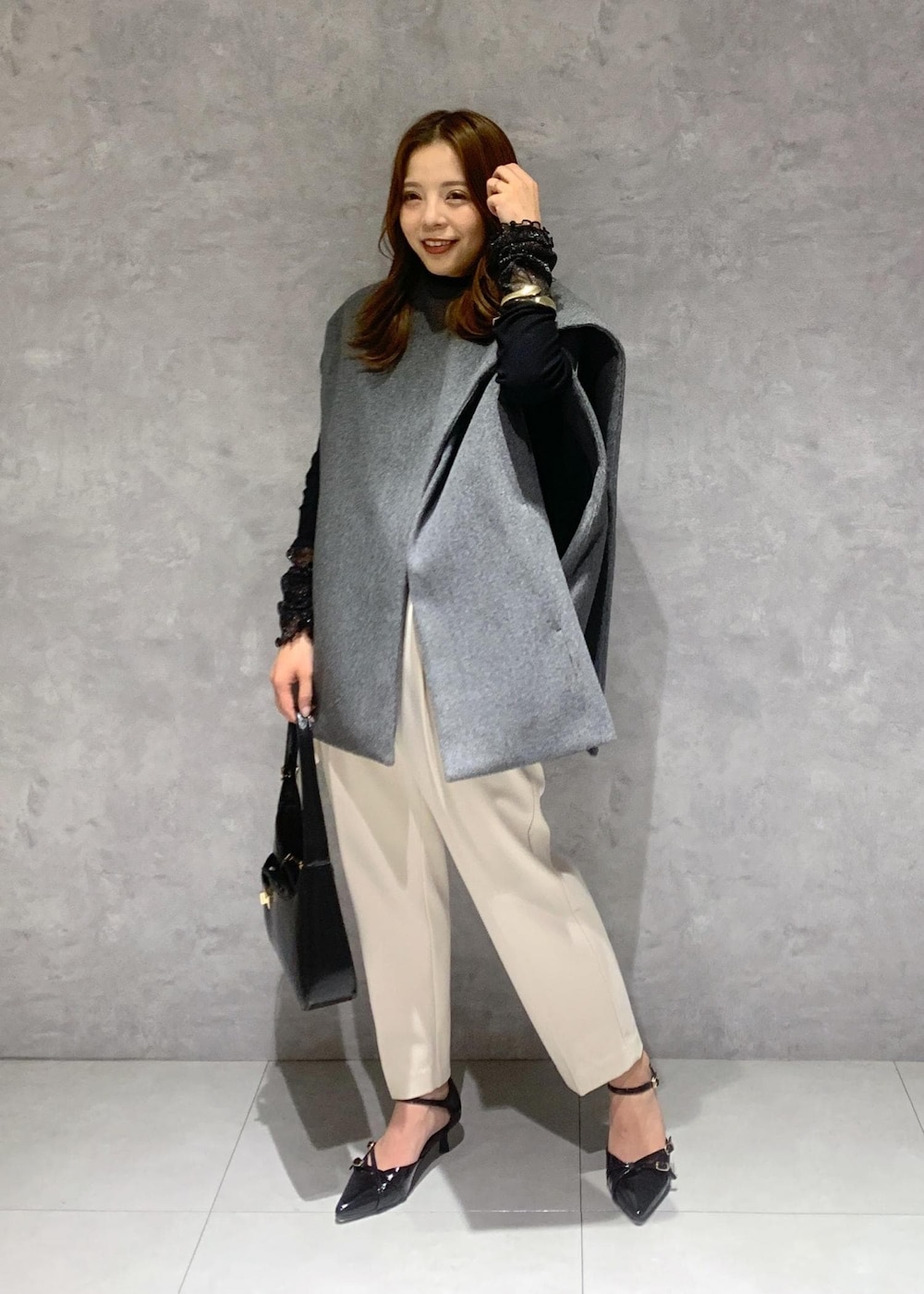 ブラック系のパンプス、グレー系のポンチョ、ブラック系のTシャツ/カットソーを着用したレディースの秋コーディネートの2枚目の写真