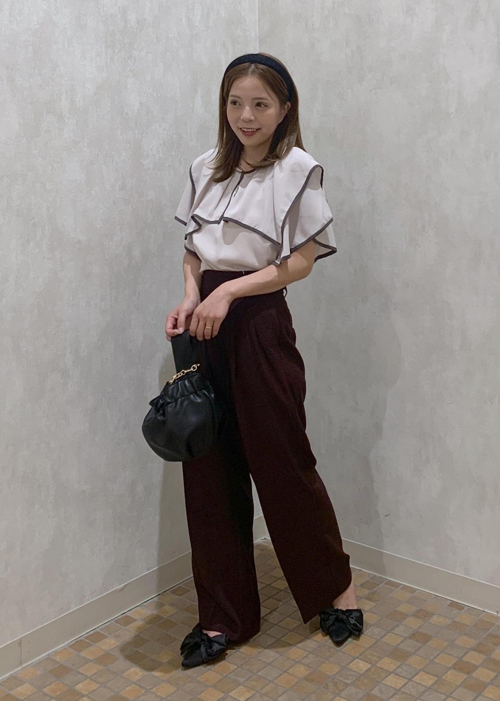 ブラウン系のスラックス、ブラック系のハンドバッグ、ブラック系のサンダルを着用したレディースの夏コーディネートの2枚目の写真