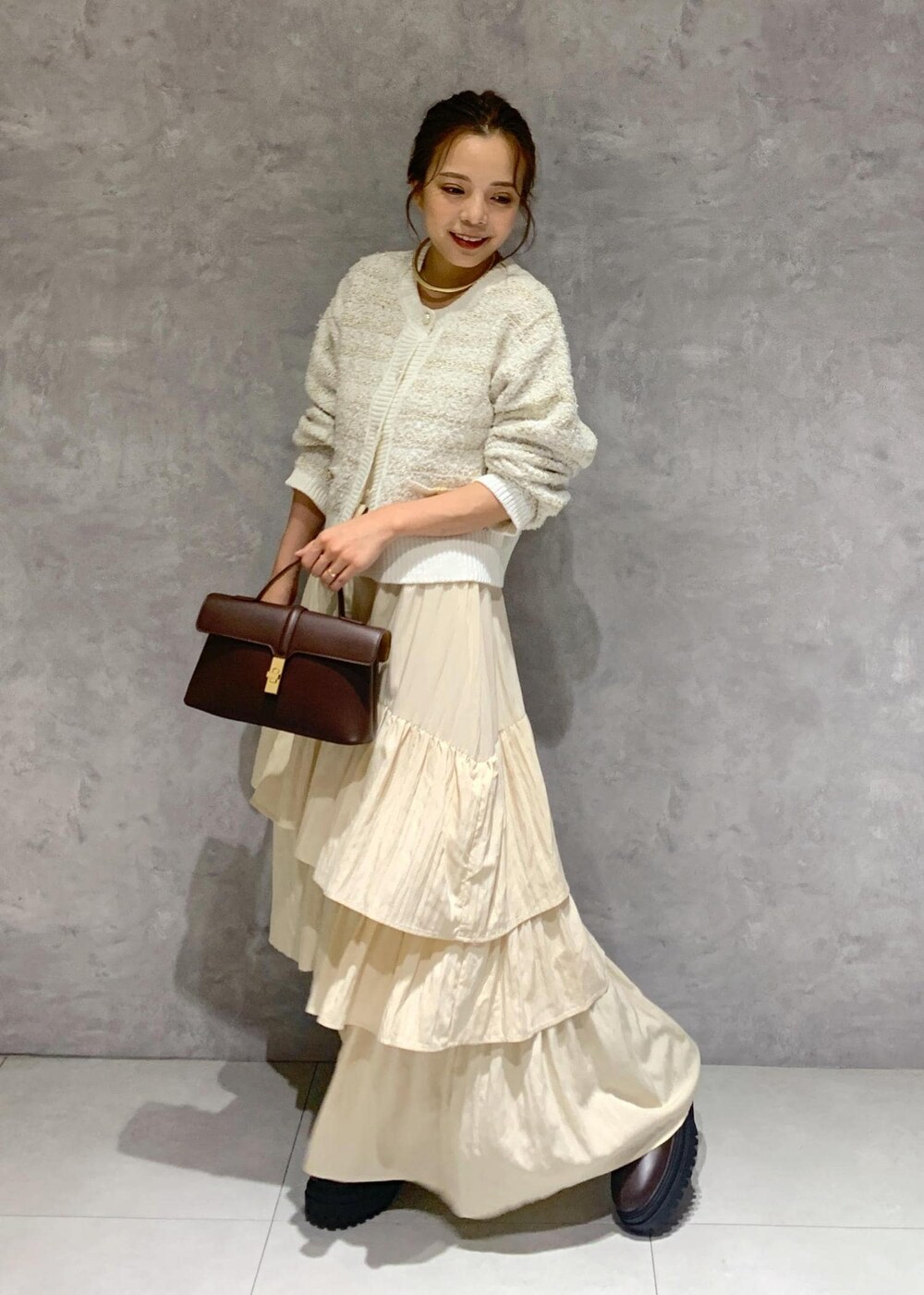 ブラウン系のショルダーバッグ、ブラウン系のブーツ、ホワイト系のカーディガン/ボレロを着用したレディースの夏コーディネートの2枚目の写真