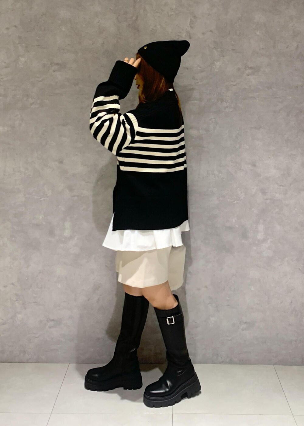 ブラック系のブーツ、ホワイト系のシャツ/ブラウス、ブラック系のニット/セーターを着用したレディースの秋コーディネートの3枚目の写真