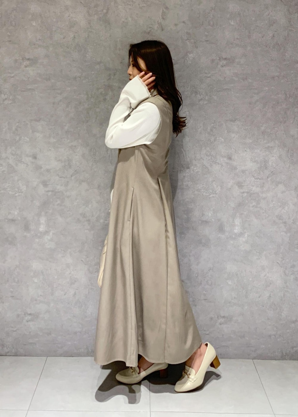 イエロー系のジャンパースカート、ホワイト系のニット/セーター、ホワイト系のローファーを着用したレディースの冬コーディネートの4枚目の写真