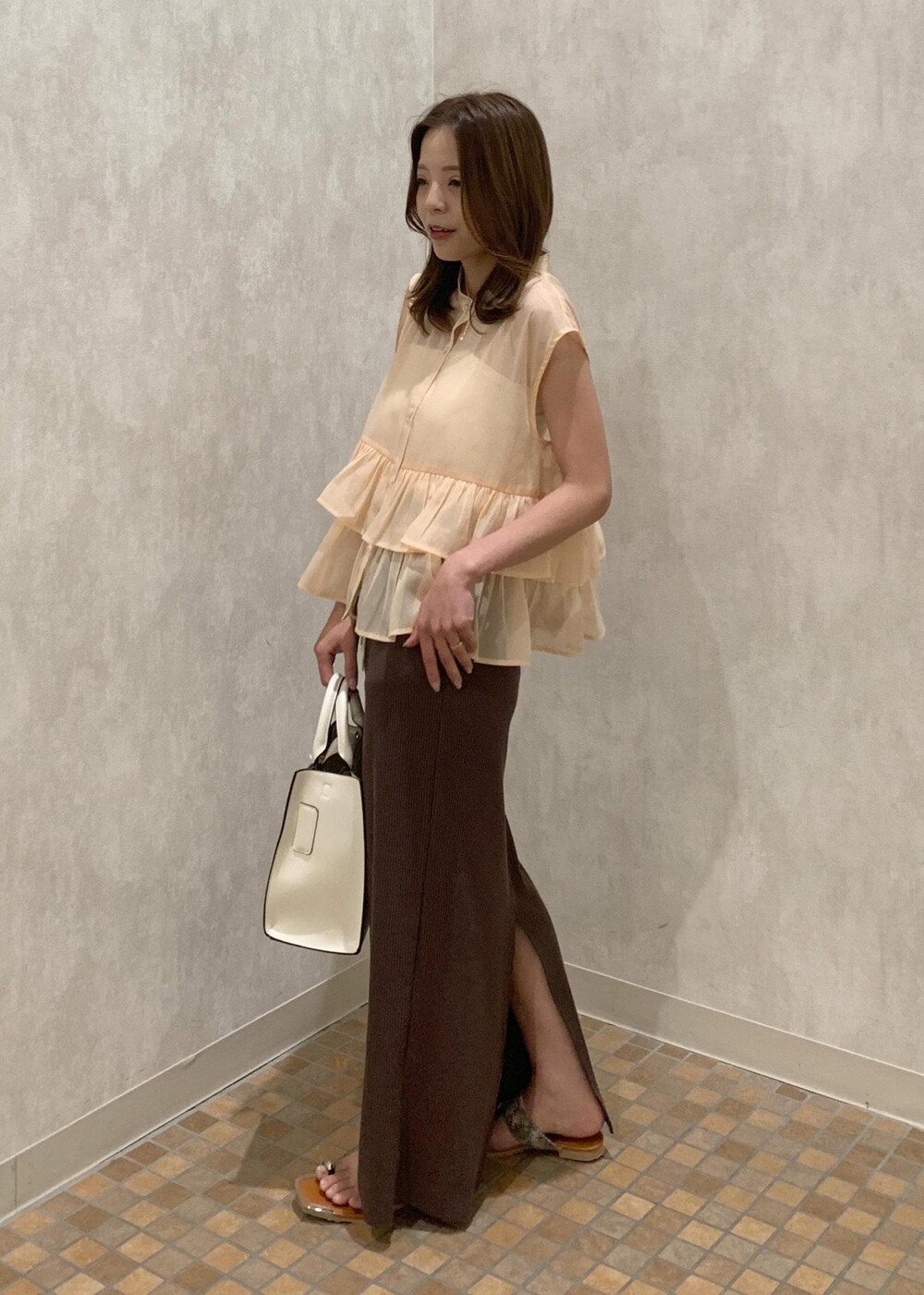 ベージュ系のサンダル、ホワイト系のハンドバッグ、ベージュ系のシャツ/ブラウスを着用したレディースの夏コーディネートの3枚目の写真