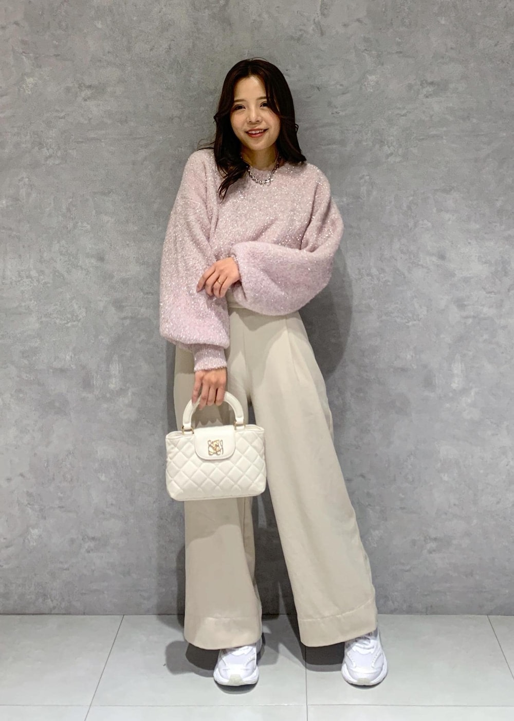 ピンク系のニット/セーター、ベージュ系のその他パンツ、ホワイト系のショルダーバッグを着用したレディースの冬コーディネートの2枚目の写真