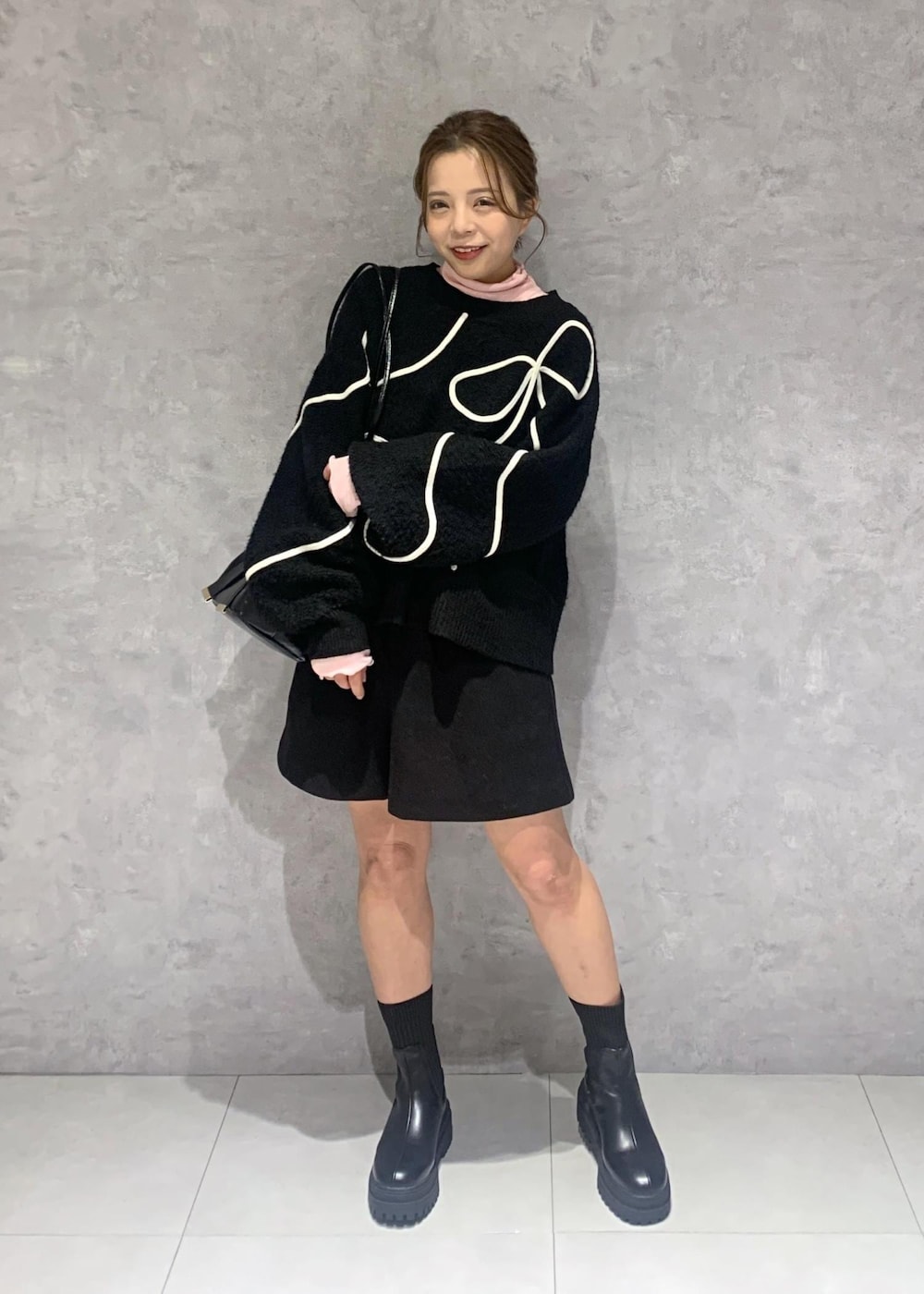 ブラック系のショルダーバッグ、ブラック系のブーツ、ブラック系のニット/セーターを着用したレディースの冬コーディネートの2枚目の写真