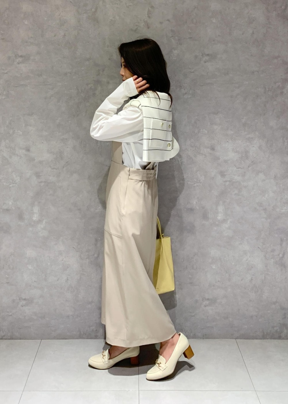 ホワイト系のTシャツ/カットソー、イエロー系のトートバッグ、ベージュ系のジャンパースカートを着用したレディースの冬コーディネートの4枚目の写真