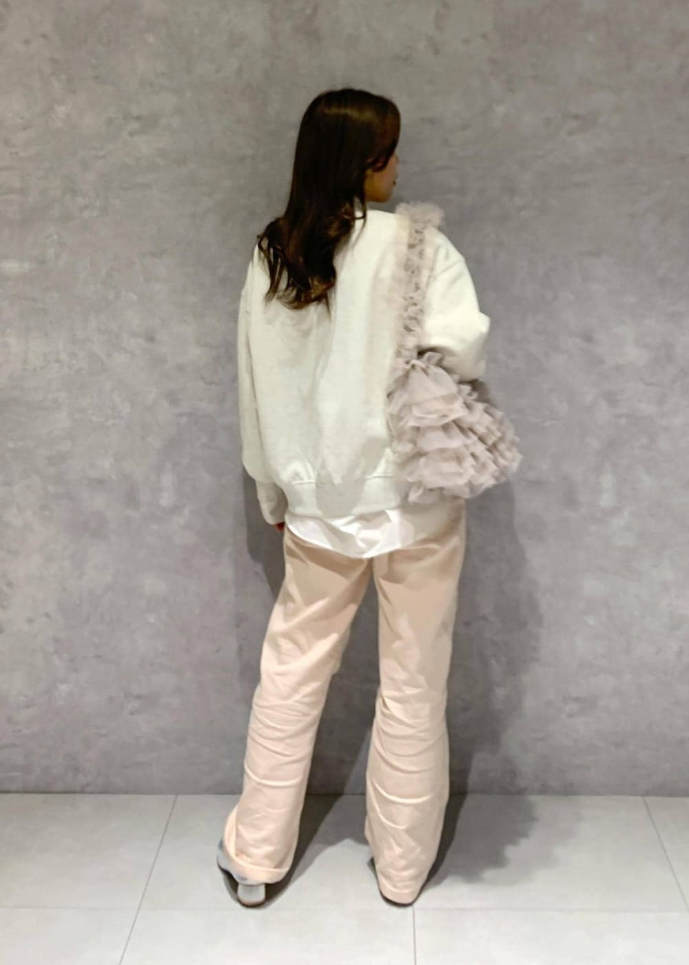 シルバー系のパンプス、ピンク系のデニムパンツ、ベージュ系のショルダーバッグを着用したレディースの冬コーディネートの6枚目の写真