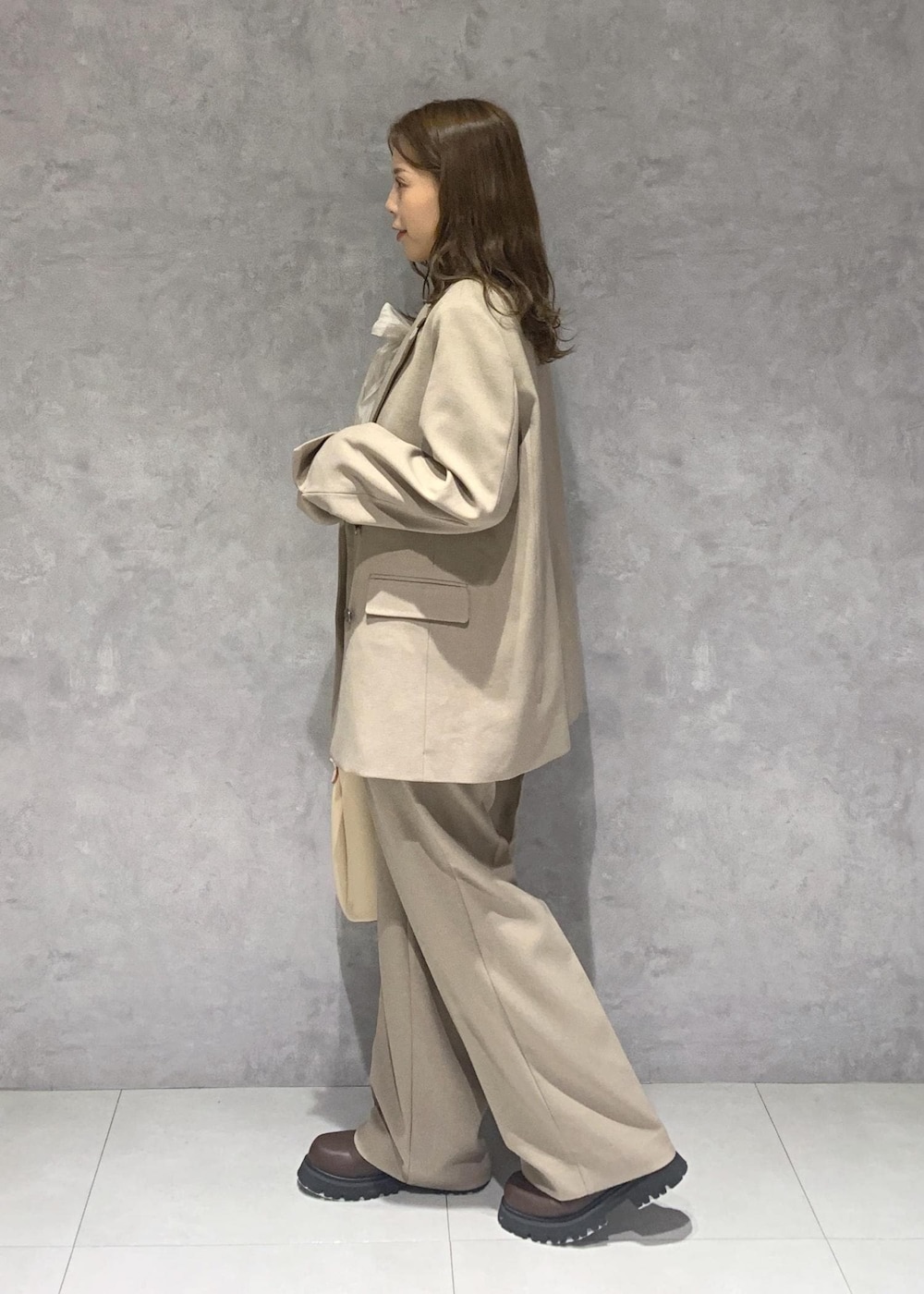 ブラウン系のブーツ、ベージュ系のショルダーバッグ、ベージュ系のスラックスを着用したレディースの秋コーディネートの3枚目の写真