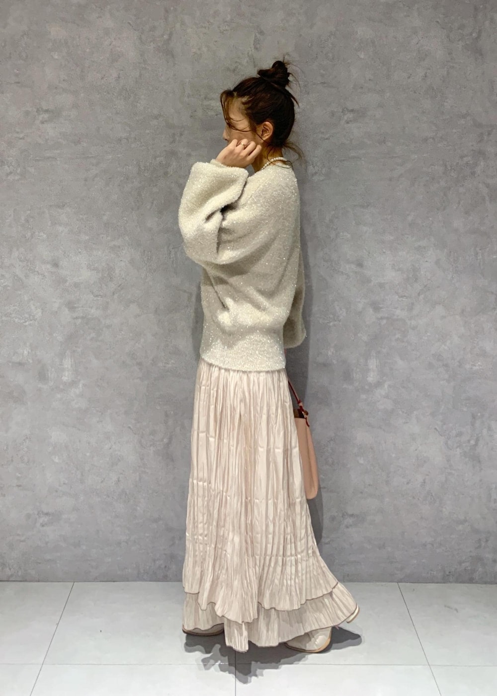 ピンク系のショルダーバッグ、ホワイト系のブーツ、ベージュ系のスカートを着用したレディースの冬コーディネートの4枚目の写真