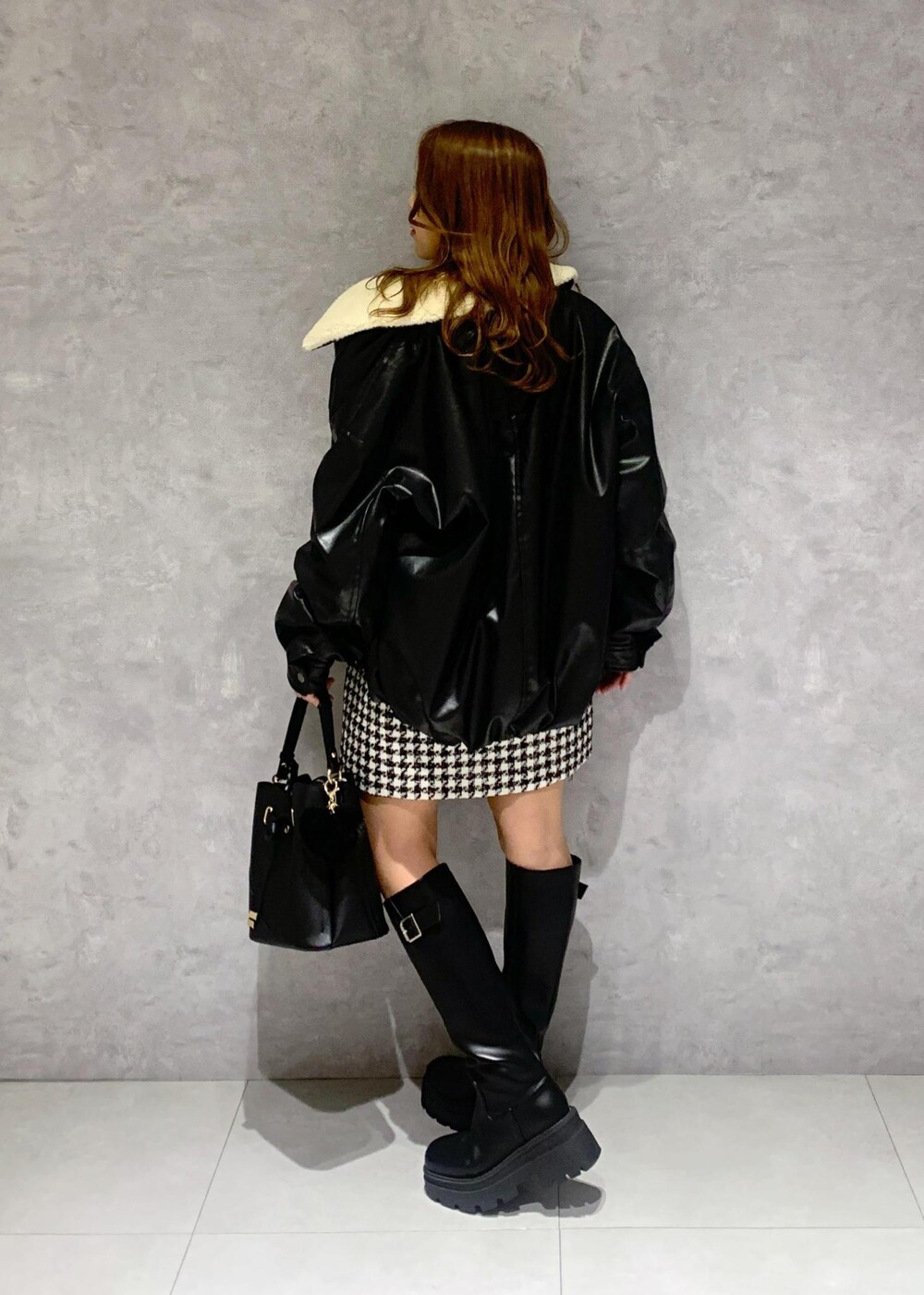 ブラック系のショルダーバッグ、ブラック系のブーツ、レッド系のニット/セーターを着用したレディースの冬コーディネートの6枚目の写真