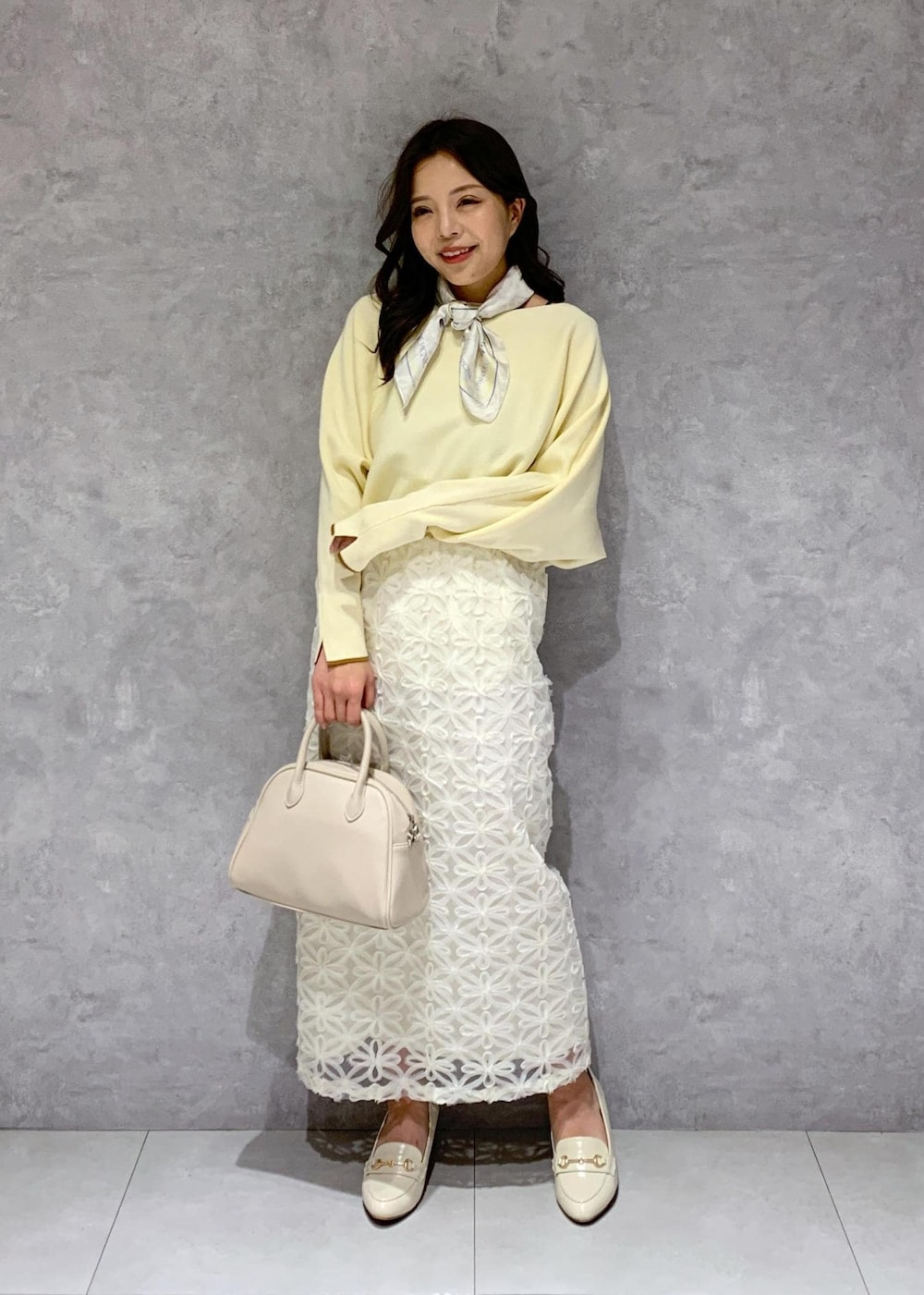 ホワイト系のスカート、ベージュ系のニット/セーター、ホワイト系のローファーを着用したレディースの冬コーディネートの2枚目の写真