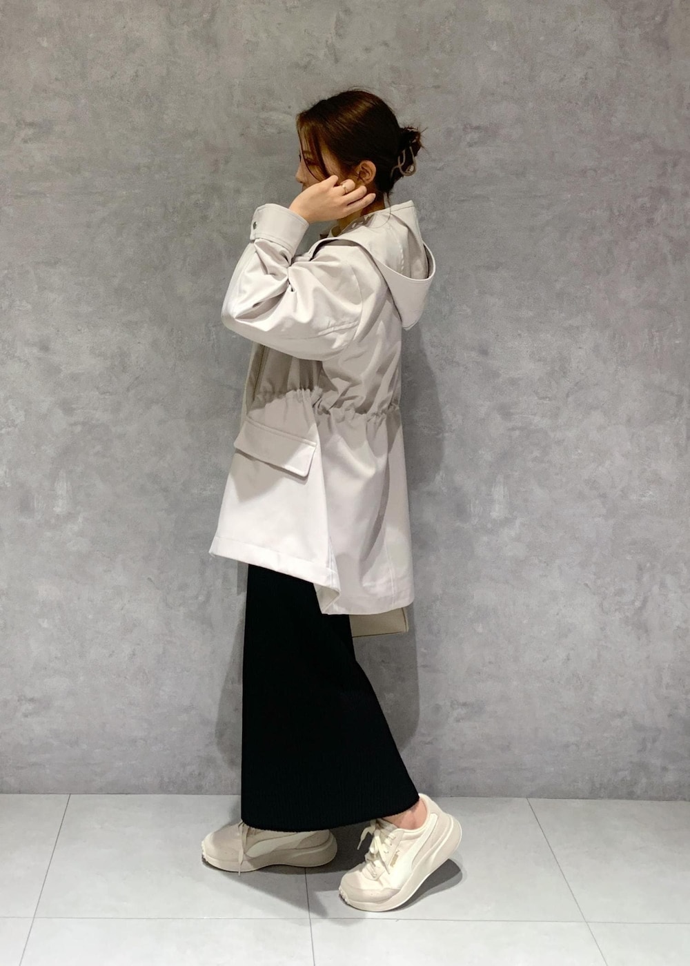 ブラック系のスカート、ベージュ系のボストンバッグ、グレー系のマウンテンパーカーを着用したレディースの春コーディネートの4枚目の写真