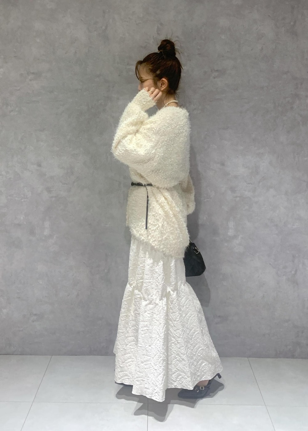 ホワイト系のカーディガン/ボレロ、ブラック系のパンプス、ホワイト系のスカートを着用したレディースの冬コーディネートの4枚目の写真