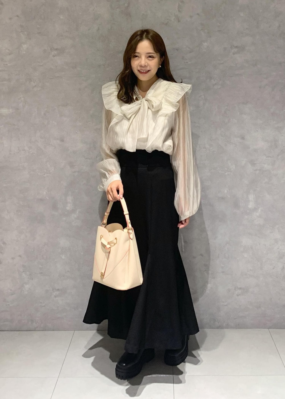 ブラック系のブーツ、ベージュ系のショルダーバッグ、ベージュ系のシャツ/ブラウスを着用したレディースの秋コーディネートの2枚目の写真