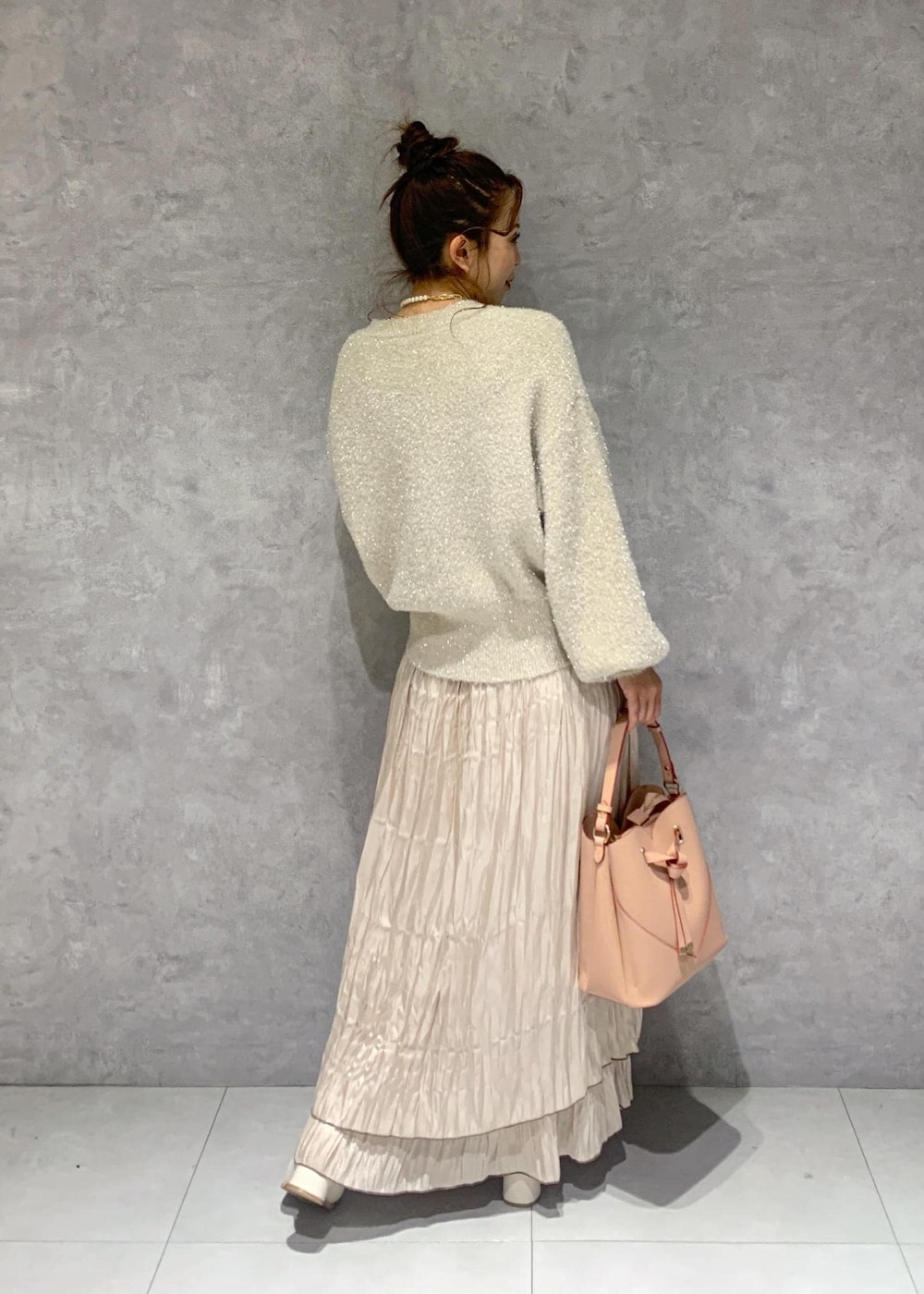 ピンク系のショルダーバッグ、ホワイト系のブーツ、ベージュ系のスカートを着用したレディースの冬コーディネートの6枚目の写真