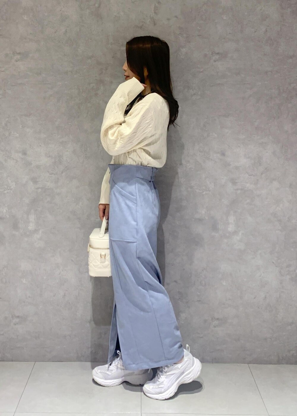 ホワイト系のハンドバッグ、ホワイト系のカーディガン/ボレロ、ブルー系のスカートを着用したレディースの冬コーディネートの4枚目の写真