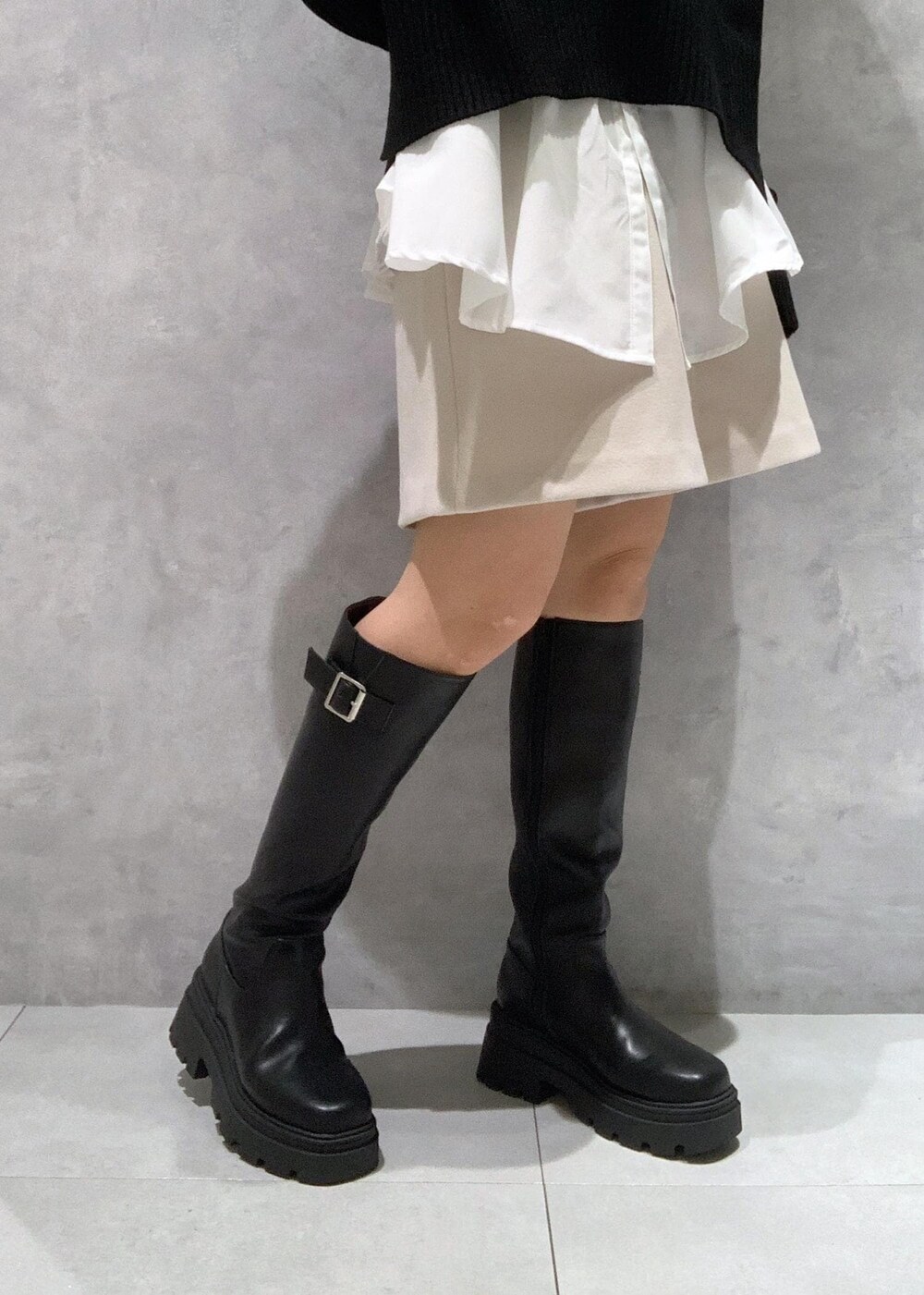 ブラック系のブーツ、ホワイト系のシャツ/ブラウス、ブラック系のニット/セーターを着用したレディースの秋コーディネートの9枚目の写真