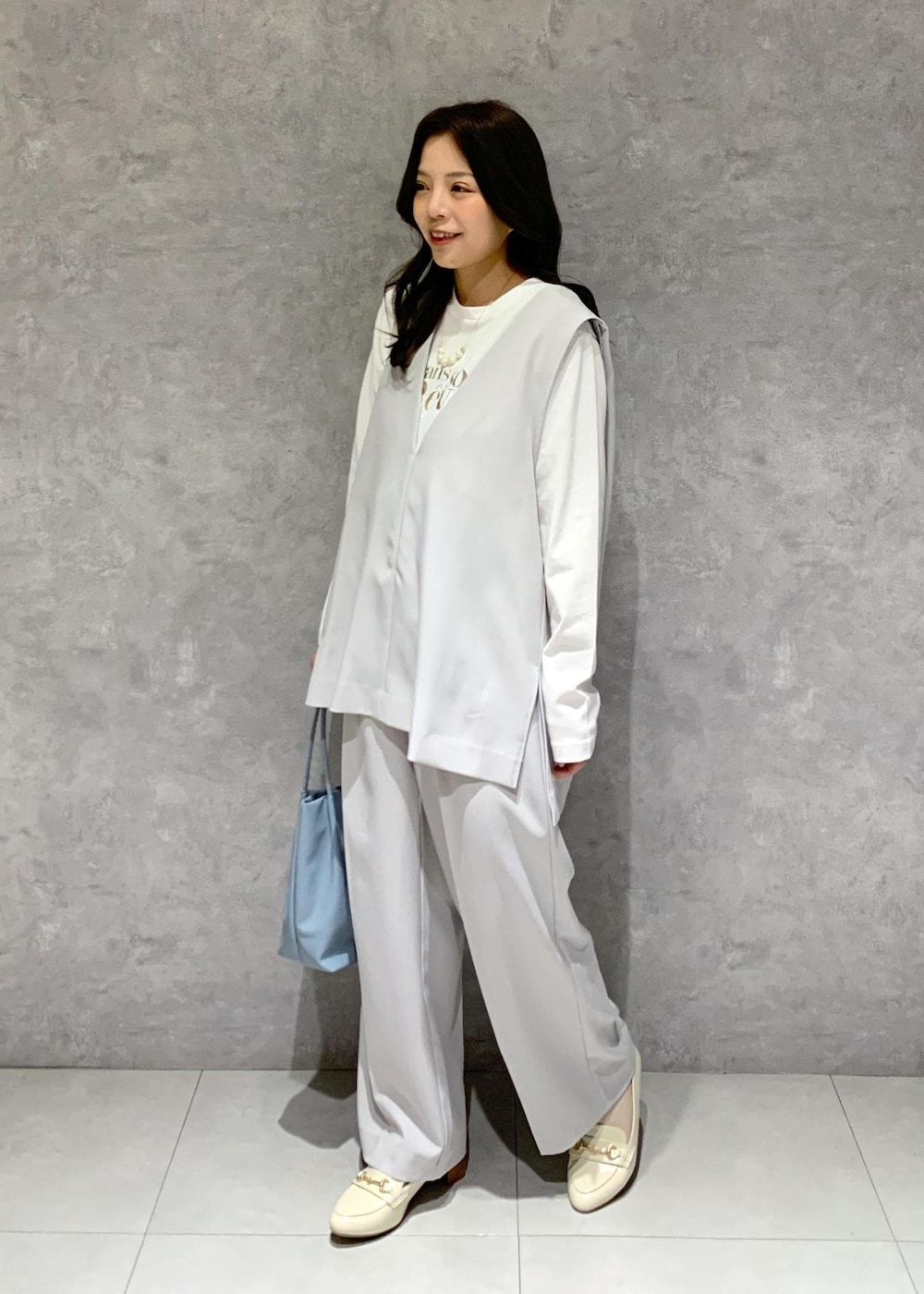 ブルー系のトートバッグ、ホワイト系のTシャツ/カットソー、ホワイト系のローファーを着用したレディースの冬コーディネートの3枚目の写真