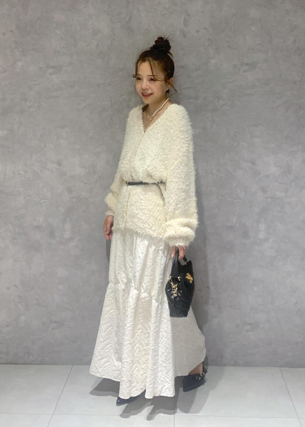 ホワイト系のカーディガン/ボレロ、ブラック系のパンプス、ホワイト系のスカートを着用したレディースの冬コーディネートの3枚目の写真