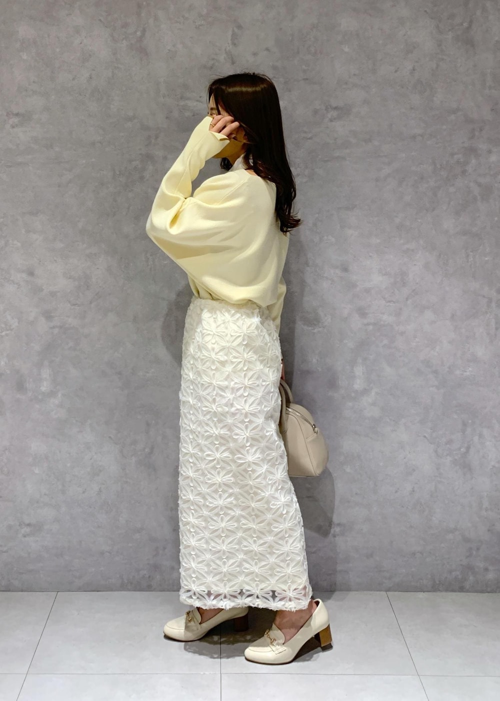 ホワイト系のスカート、ベージュ系のニット/セーター、ホワイト系のローファーを着用したレディースの冬コーディネートの4枚目の写真