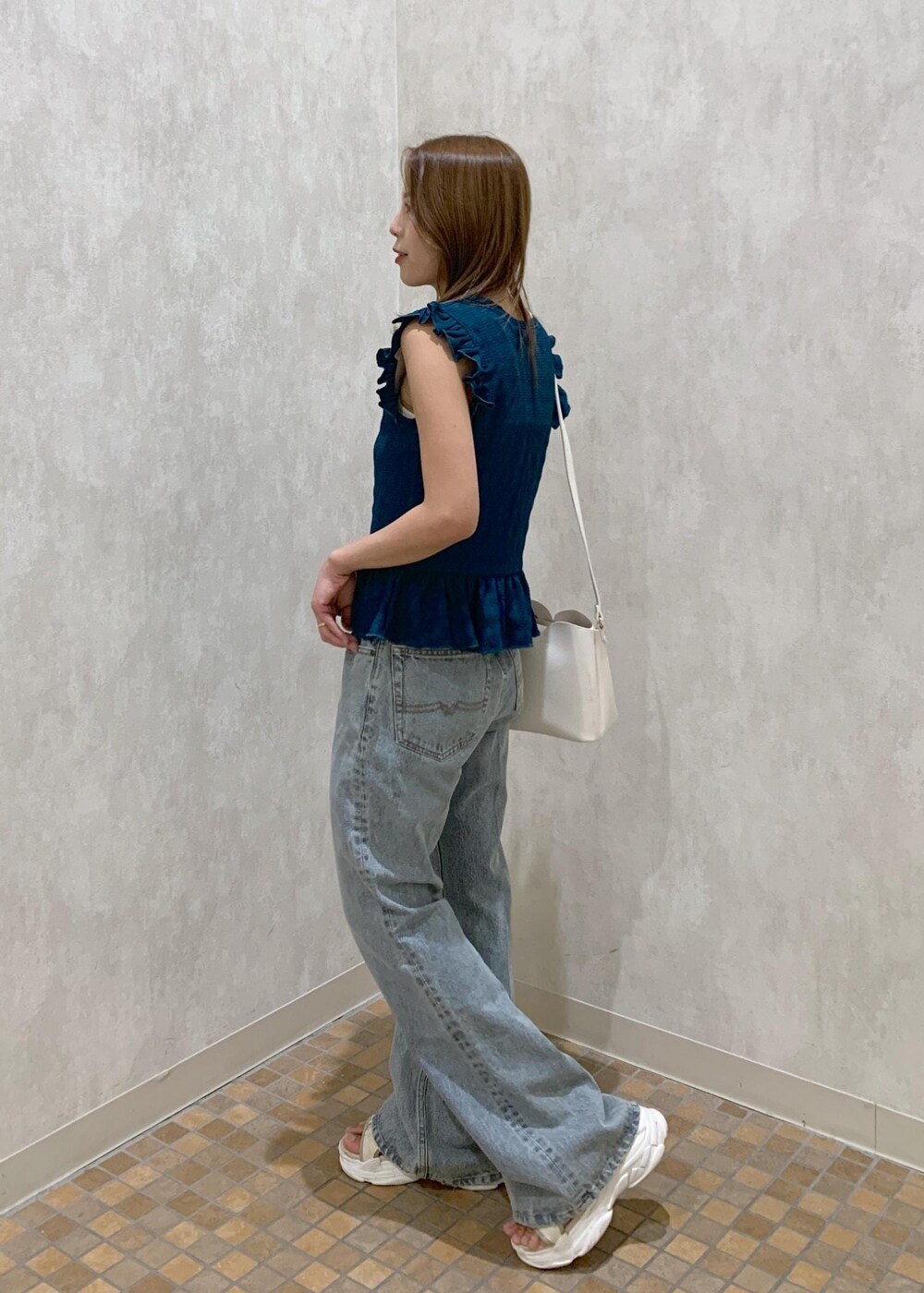 ベージュ系のサンダル、ホワイト系のショルダーバッグ、ブルー系のデニムパンツを着用したレディースの夏コーディネートの3枚目の写真