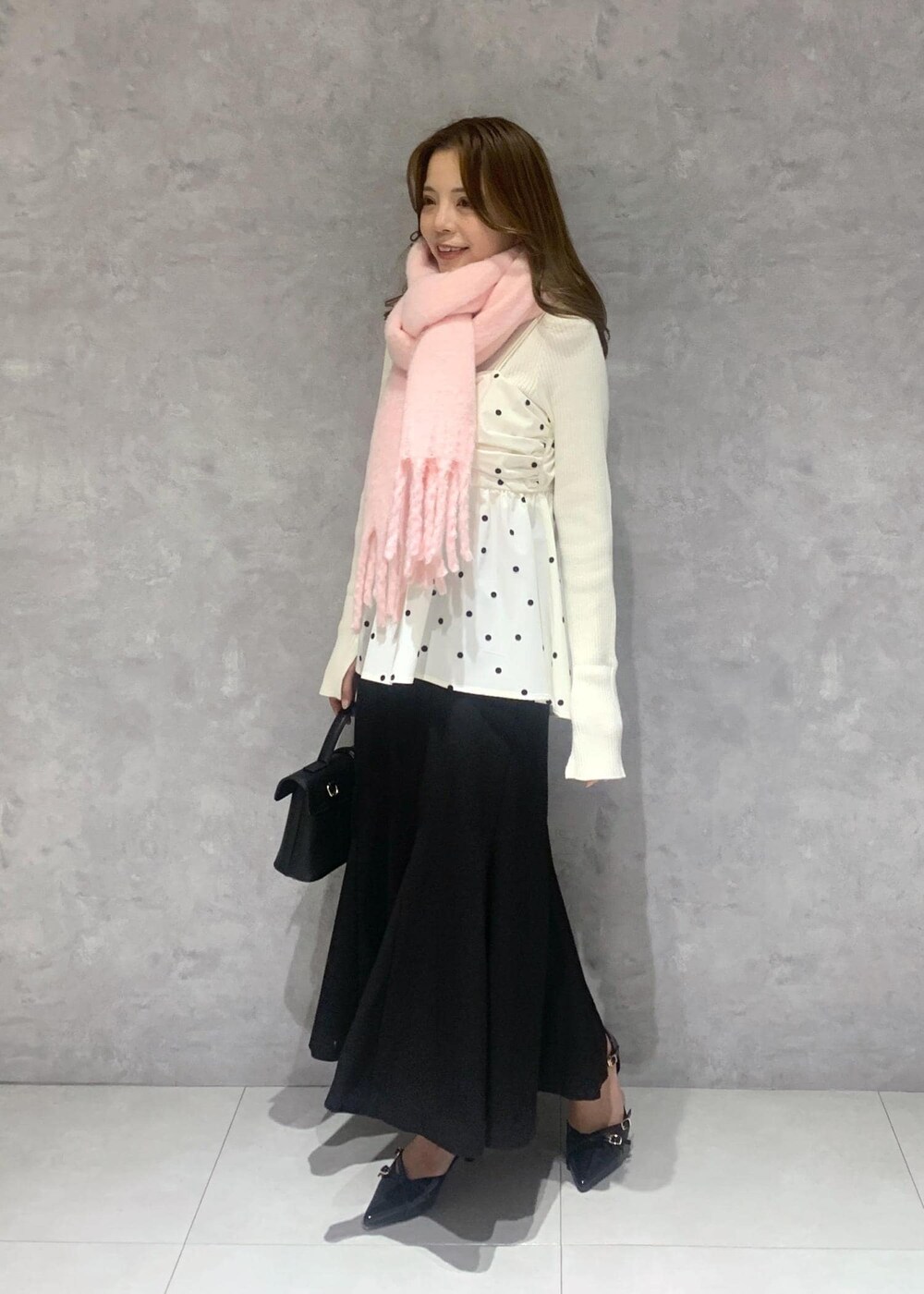 ブラック系のショルダーバッグ、ホワイト系のニット/セーター、ブラック系のスカートを着用したレディースの冬コーディネートの3枚目の写真