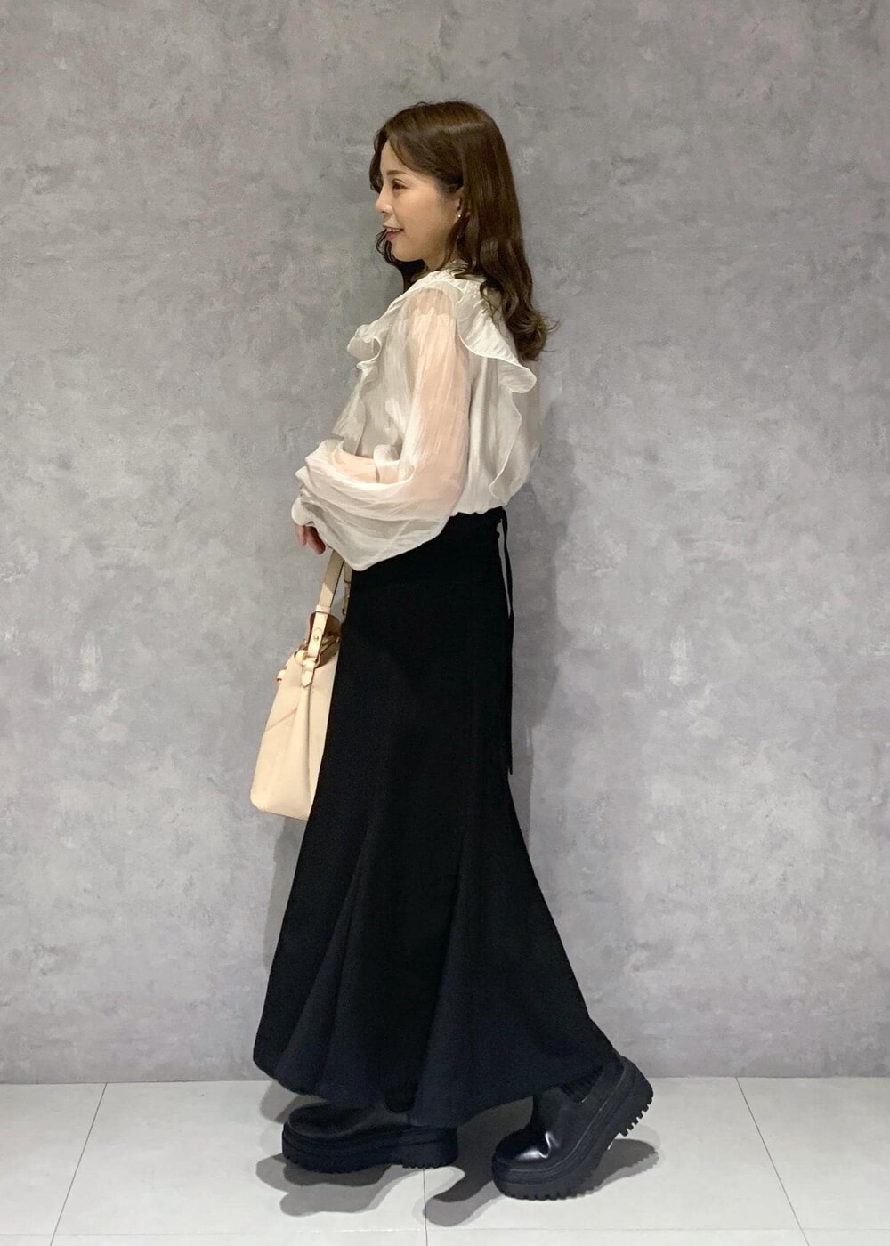 ブラック系のブーツ、ベージュ系のショルダーバッグ、ベージュ系のシャツ/ブラウスを着用したレディースの秋コーディネートの3枚目の写真