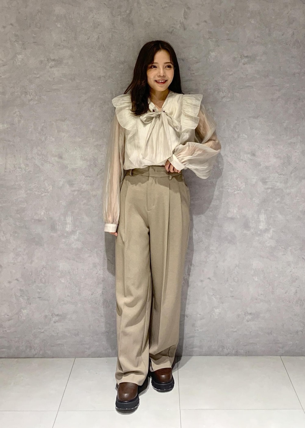 ブラウン系のブーツ、ベージュ系のショルダーバッグ、ベージュ系のスラックスを着用したレディースの秋コーディネートの6枚目の写真