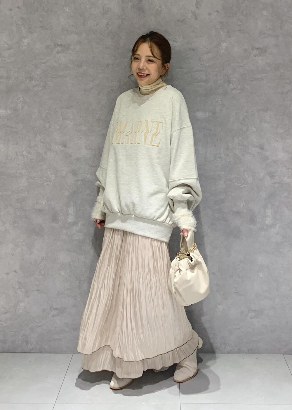 ホワイト系のブーツ、ベージュ系のスカート、ホワイト系のニット/セーターを着用したレディースの秋コーディネートの2枚目の写真