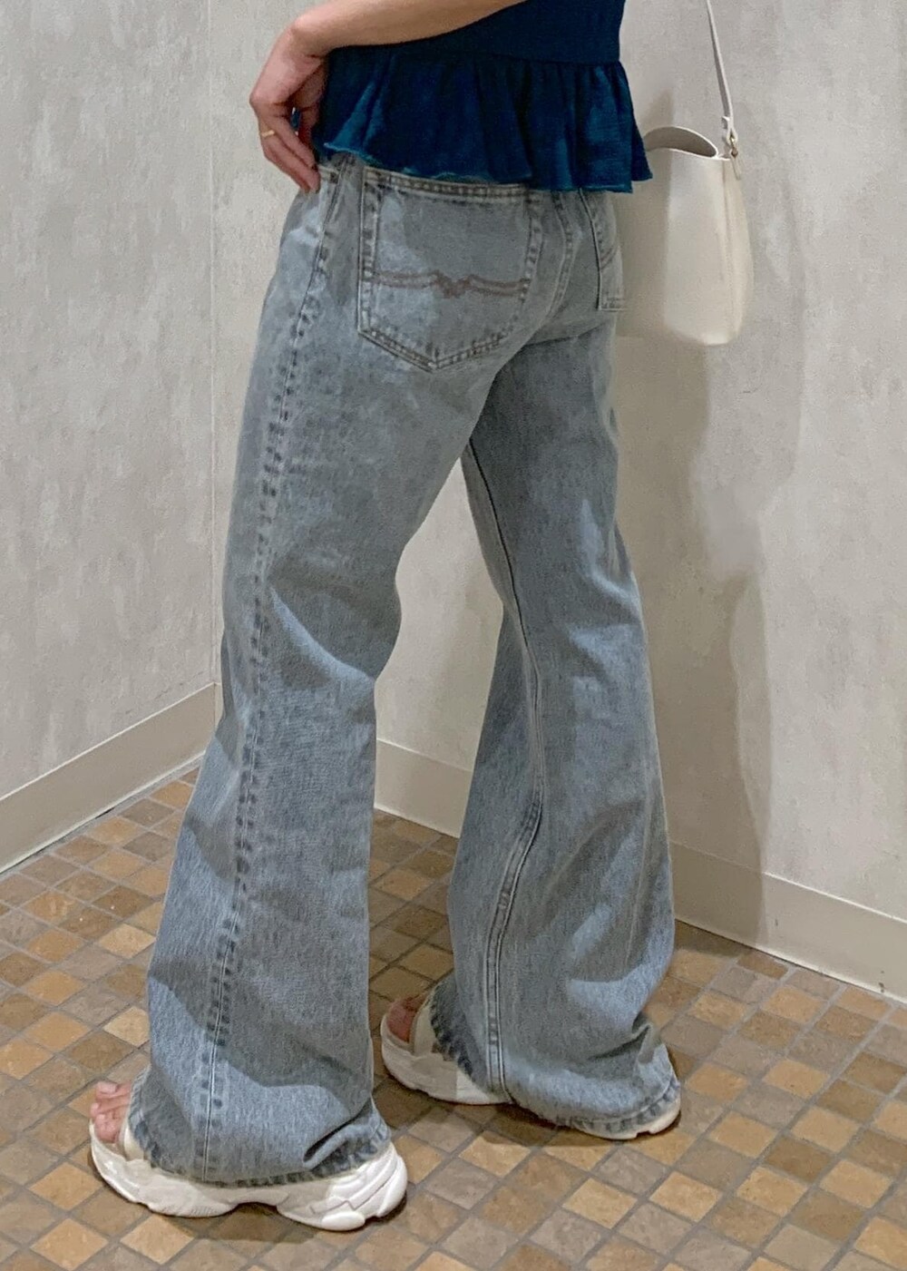 ベージュ系のサンダル、ホワイト系のショルダーバッグ、ブルー系のデニムパンツを着用したレディースの夏コーディネートの5枚目の写真