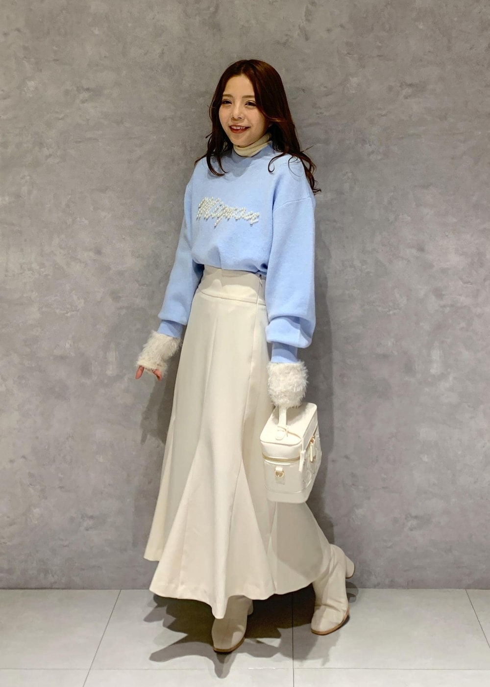 ホワイト系のニット/セーター、ホワイト系のブーツ、ホワイト系のハンドバッグを着用したレディースの冬コーディネートの3枚目の写真