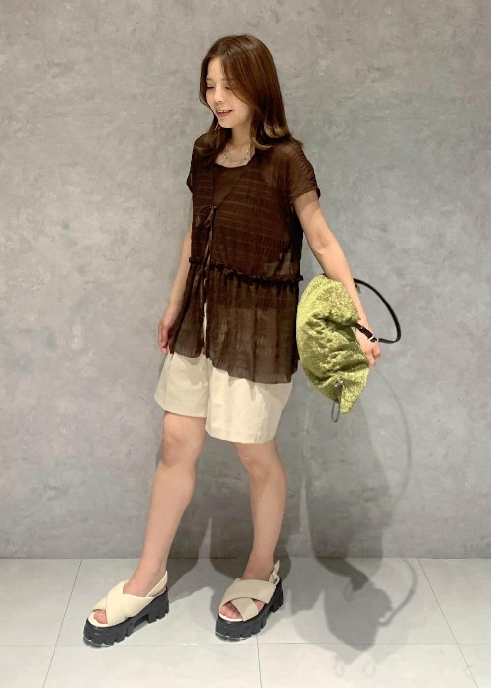 ホワイト系のサンダル、ゴールド系のショルダーバッグ、ブラウン系のTシャツ/カットソーを着用したレディースの夏コーディネートの2枚目の写真