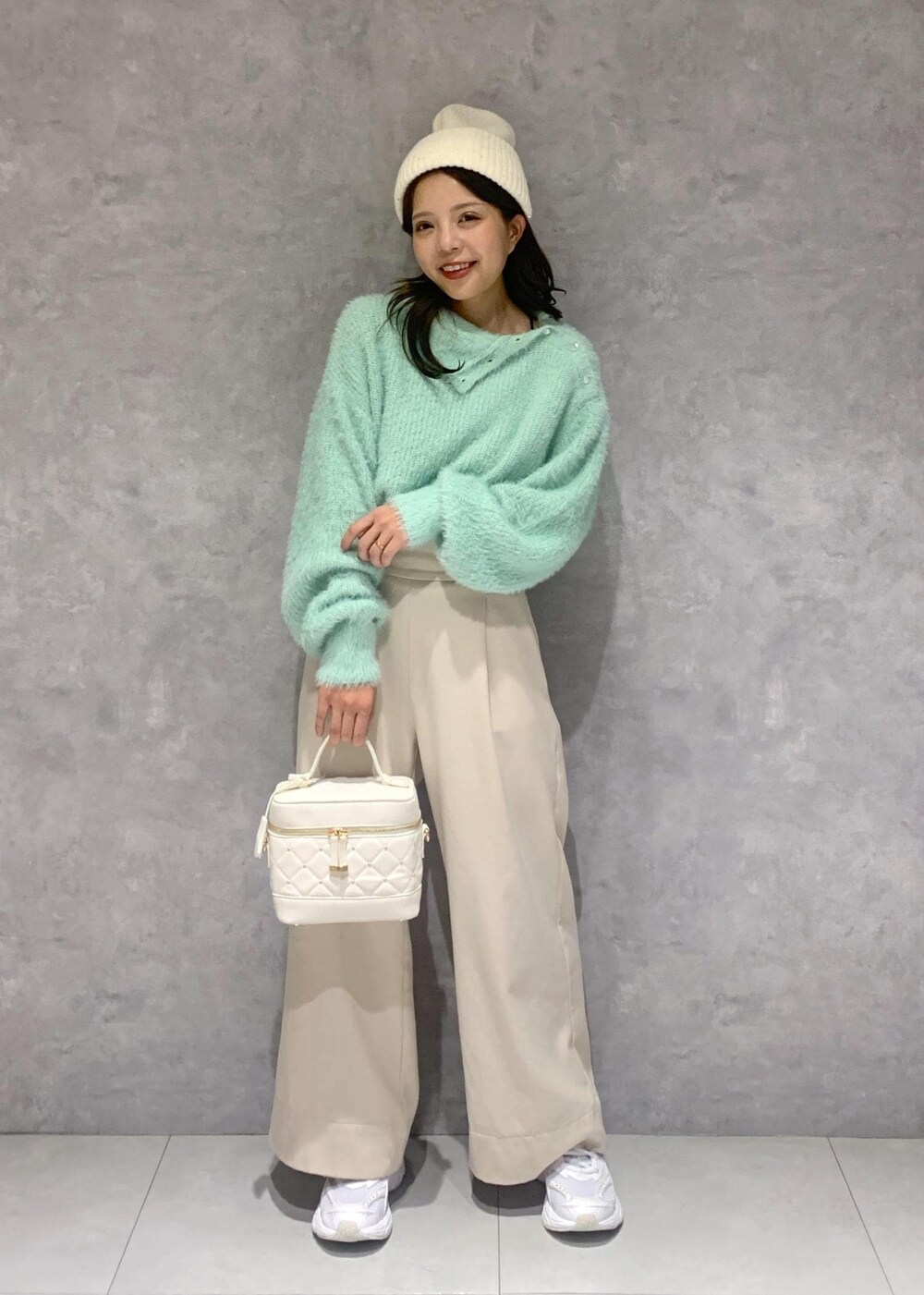 ホワイト系のハンドバッグ、ベージュ系のその他パンツ、グリーン系のニット/セーターを着用したレディースの冬コーディネートの2枚目の写真