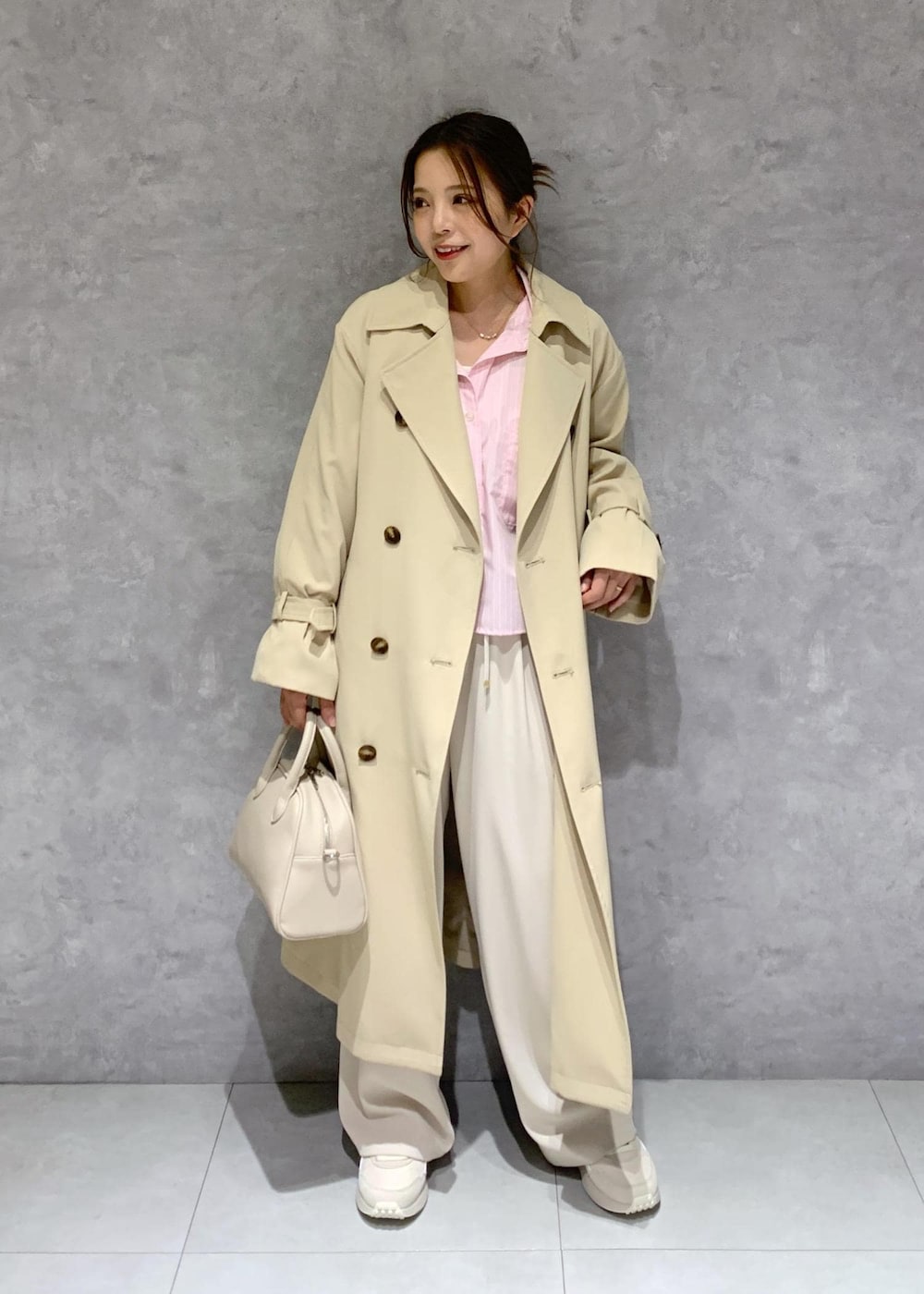 ベージュ系のボストンバッグ、ピンク系のシャツ/ブラウス、ベージュ系のトレンチコートを着用したレディースの春コーディネートの2枚目の写真