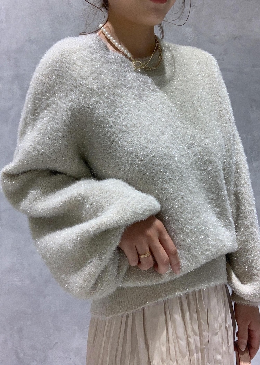 ピンク系のショルダーバッグ、ホワイト系のブーツ、ベージュ系のスカートを着用したレディースの冬コーディネートの8枚目の写真