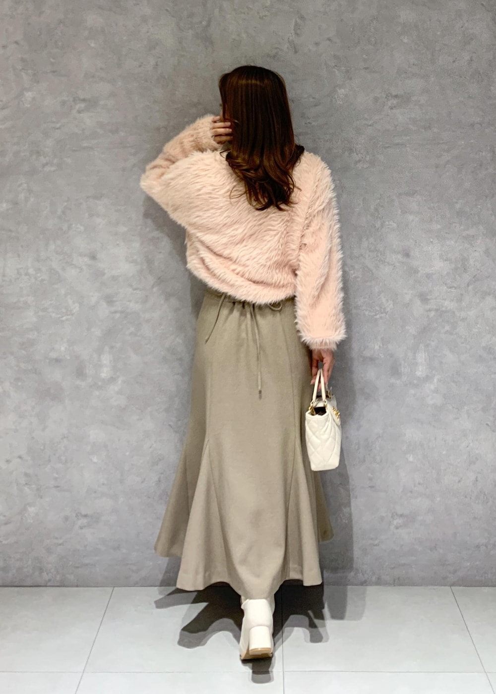 ホワイト系のブーツ、ベージュ系のスカート、ピンク系のカーディガン/ボレロを着用したレディースの冬コーディネートの5枚目の写真