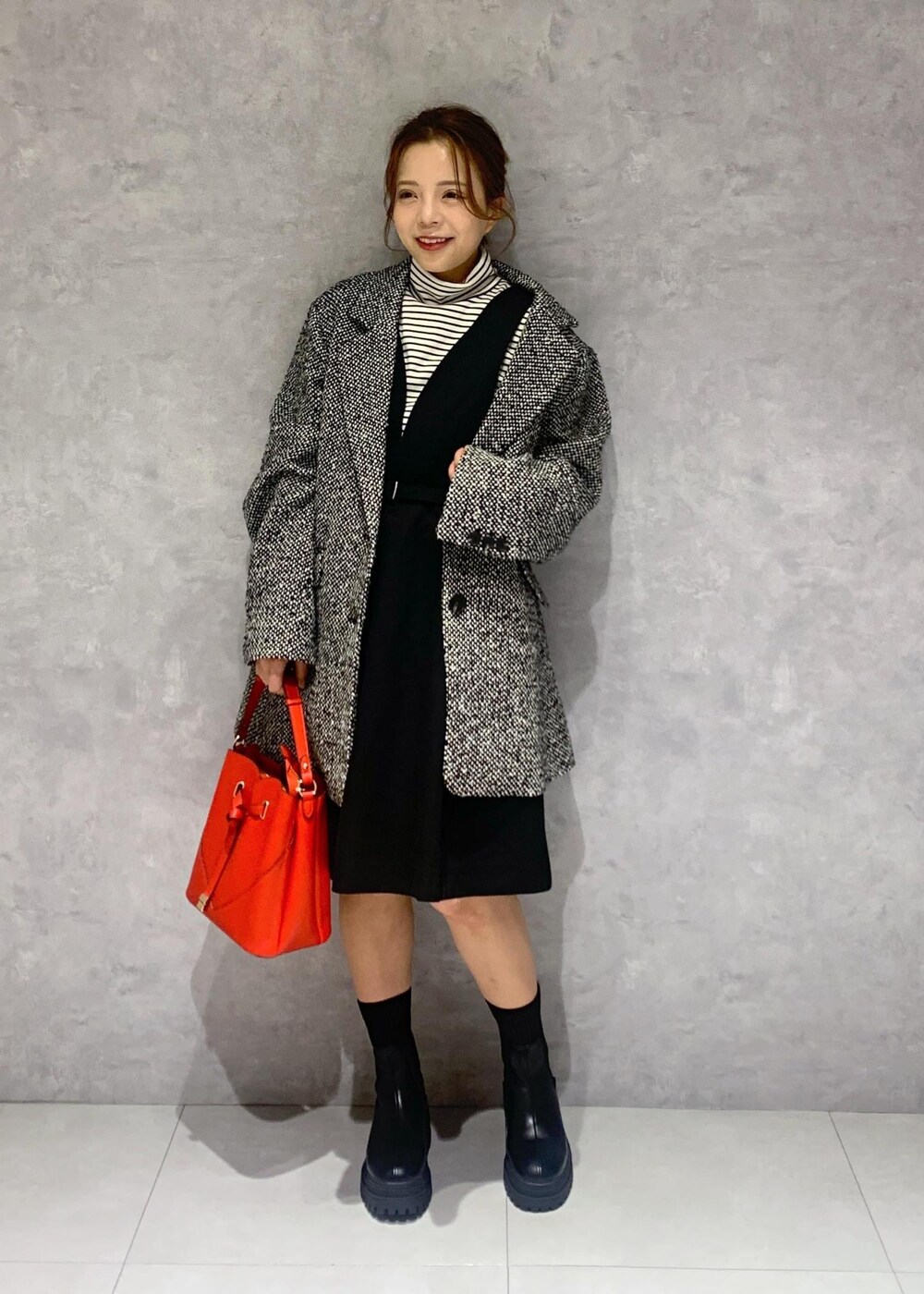 ブラック系のブーツ、レッド系のショルダーバッグ、ブラック系のワンピースを着用したレディースの冬コーディネートの2枚目の写真