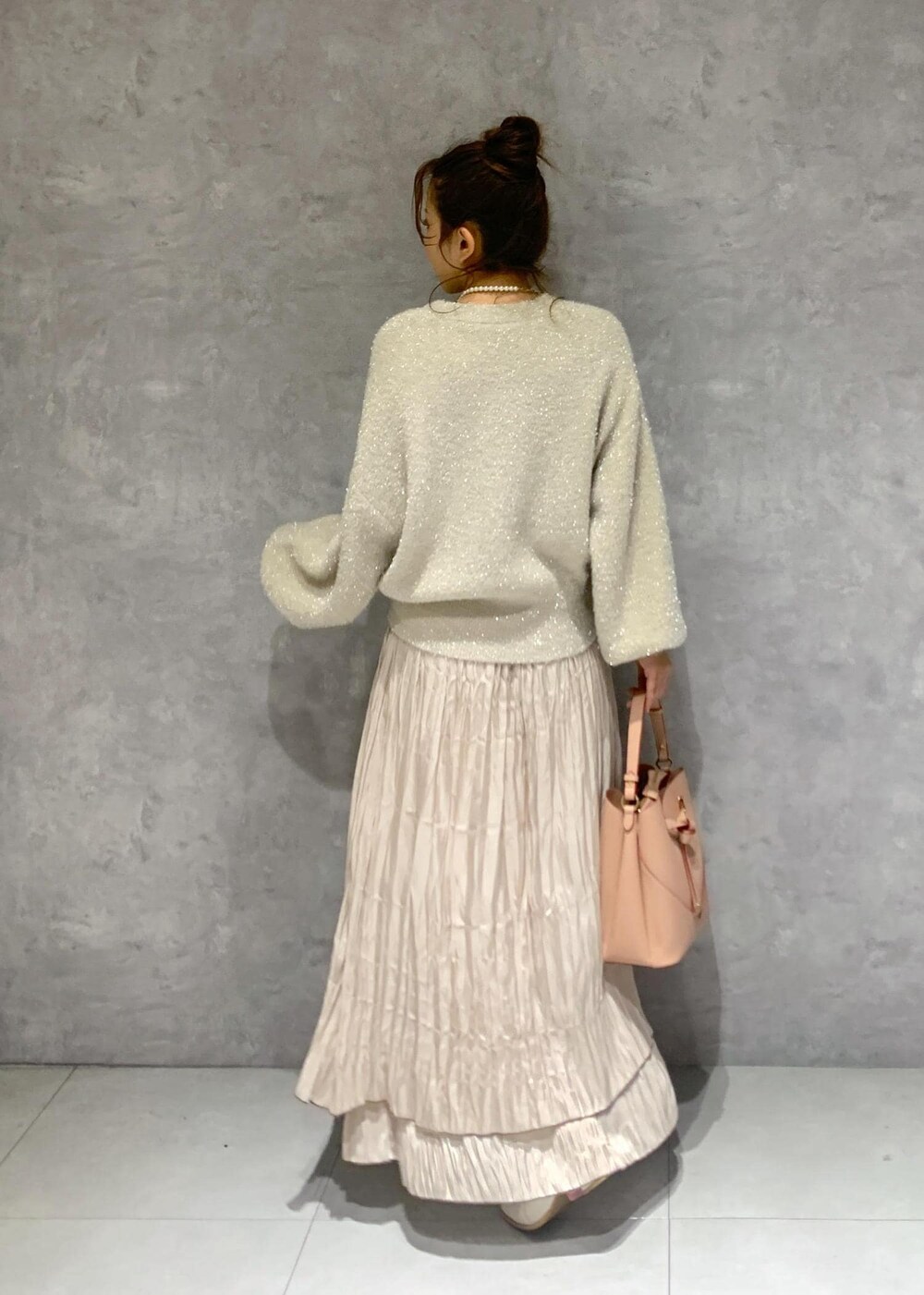 ピンク系のショルダーバッグ、ホワイト系のブーツ、ベージュ系のスカートを着用したレディースの冬コーディネートの5枚目の写真