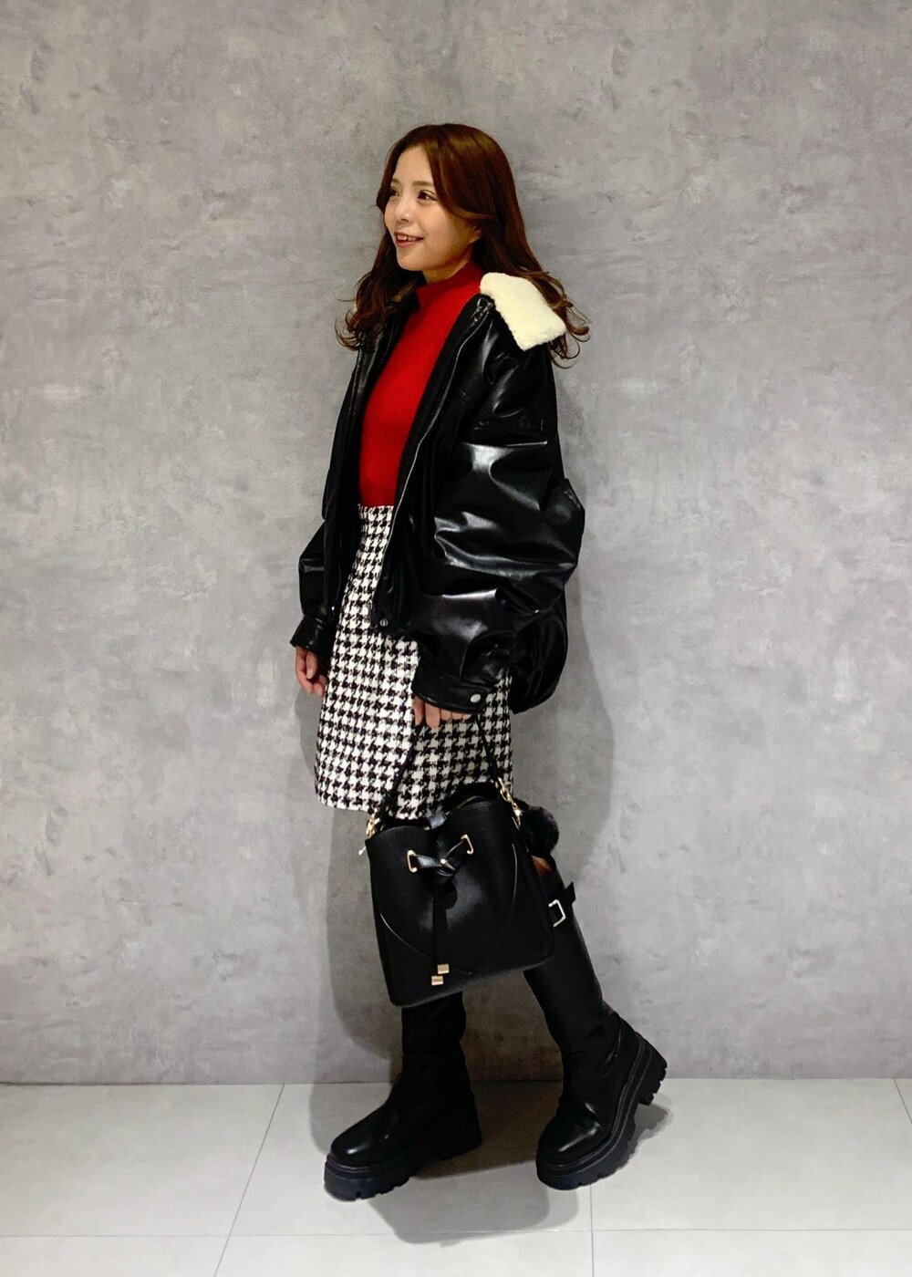 ブラック系のショルダーバッグ、ブラック系のブーツ、レッド系のニット/セーターを着用したレディースの冬コーディネートの4枚目の写真