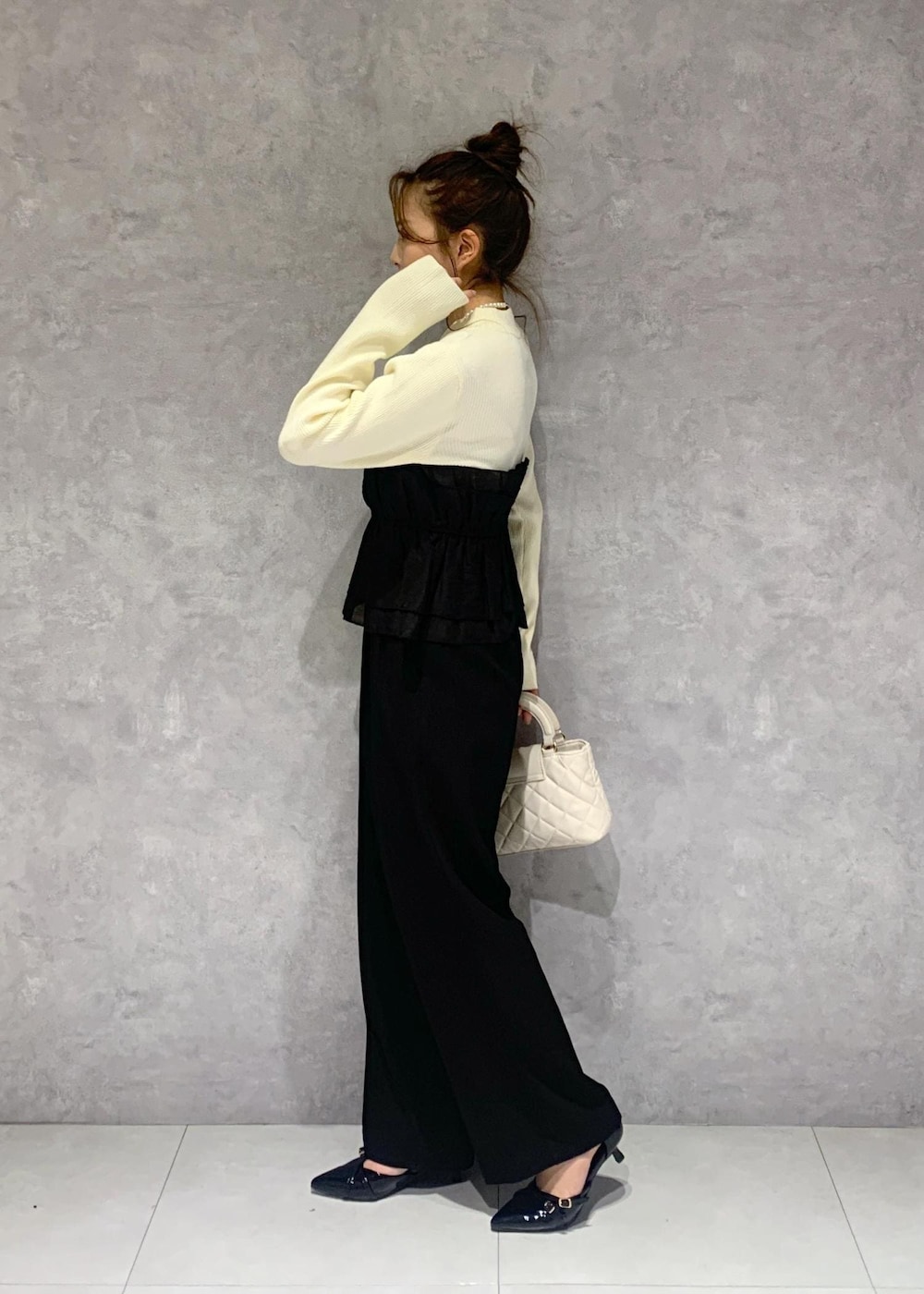 ブラック系のパンプス、ホワイト系のニット/セーター、ブラック系のスラックスを着用したレディースの冬コーディネートの4枚目の写真