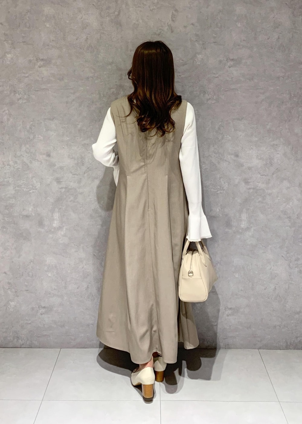 イエロー系のジャンパースカート、ホワイト系のニット/セーター、ホワイト系のローファーを着用したレディースの冬コーディネートの5枚目の写真