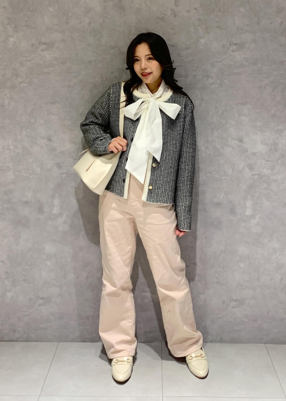 ピンク系のデニムパンツ、ホワイト系のハンドバッグ、ホワイト系のパンプスを着用したレディースの冬コーディネートの2枚目の写真