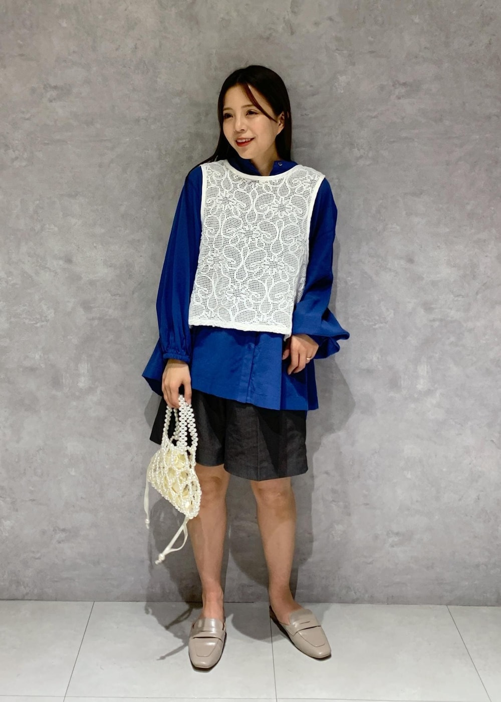 ブルー系のシャツ/ブラウス、グレー系のローファー、ホワイト系のハンドバッグを着用したレディースの春コーディネートの2枚目の写真