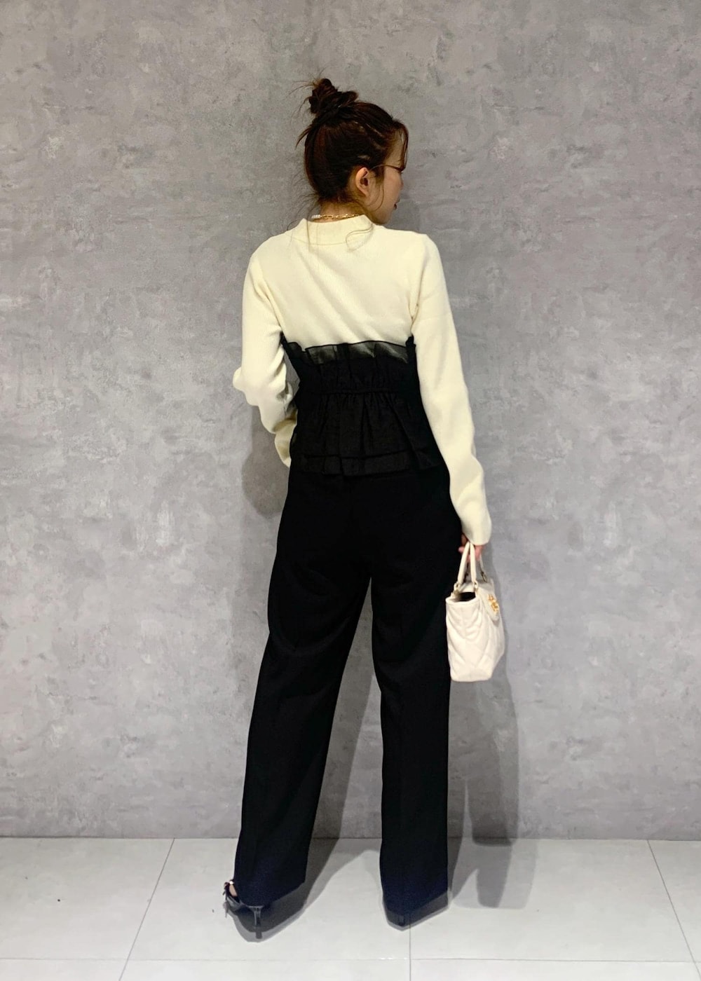 ブラック系のパンプス、ホワイト系のニット/セーター、ブラック系のスラックスを着用したレディースの冬コーディネートの6枚目の写真