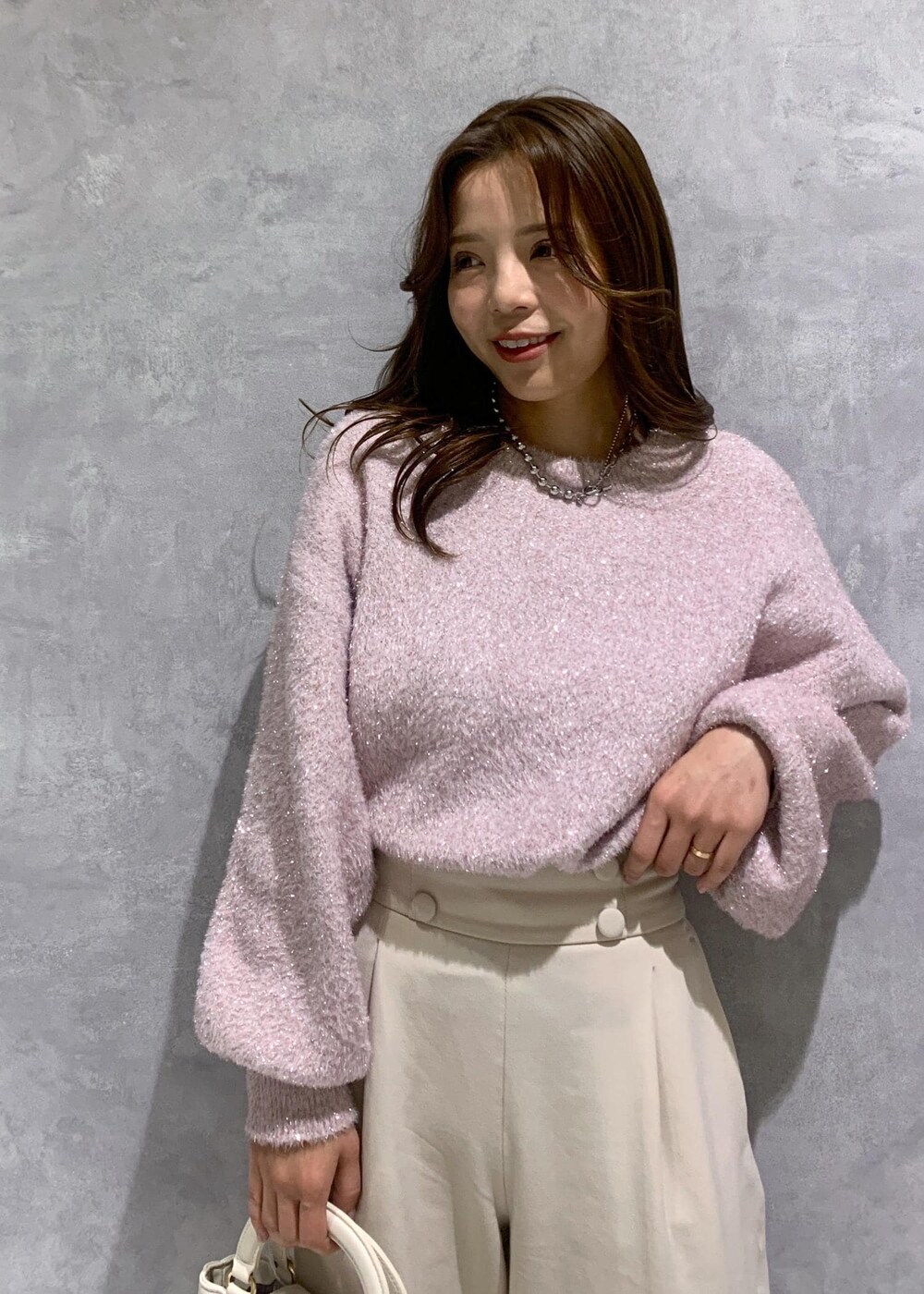 ピンク系のニット/セーター、ベージュ系のその他パンツ、ホワイト系のショルダーバッグを着用したレディースの冬コーディネートの7枚目の写真