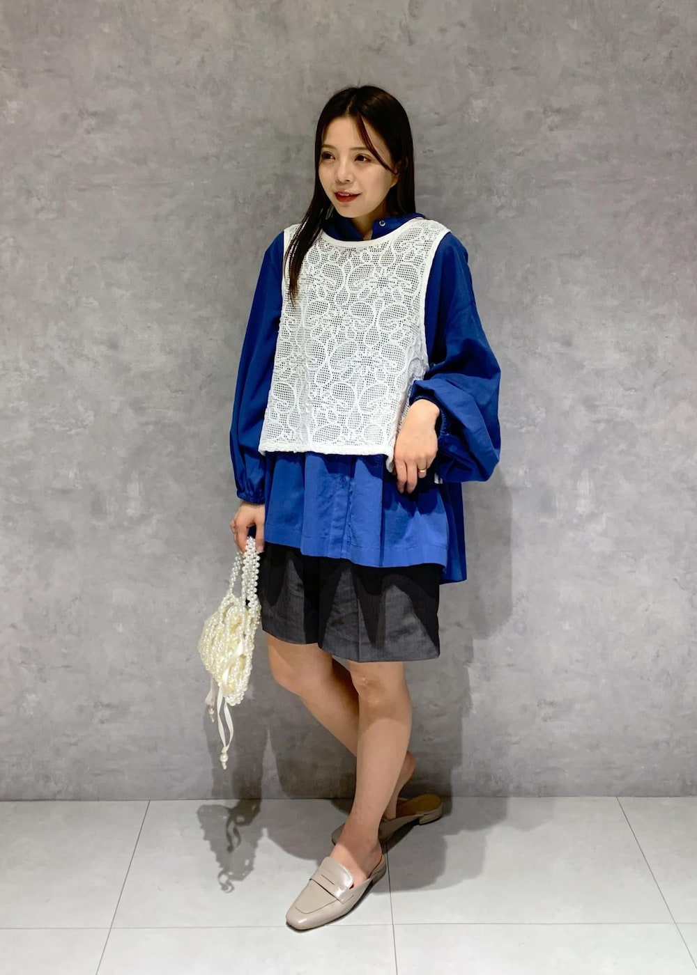 ブルー系のシャツ/ブラウス、グレー系のローファー、ホワイト系のハンドバッグを着用したレディースの春コーディネートの3枚目の写真