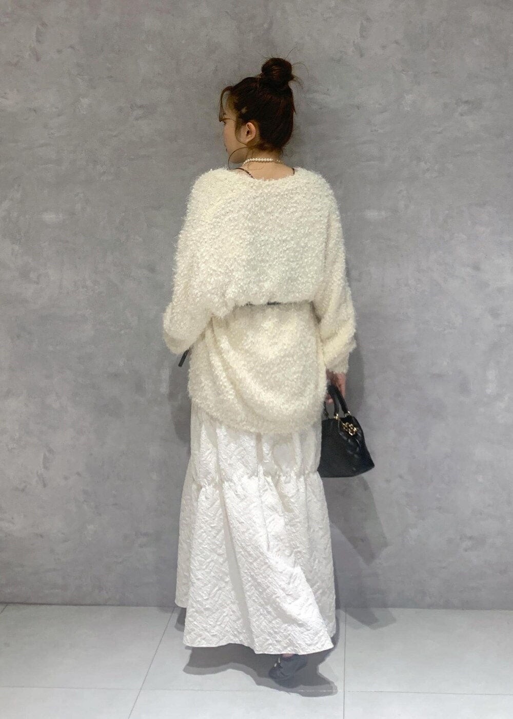 ホワイト系のカーディガン/ボレロ、ブラック系のパンプス、ホワイト系のスカートを着用したレディースの冬コーディネートの5枚目の写真