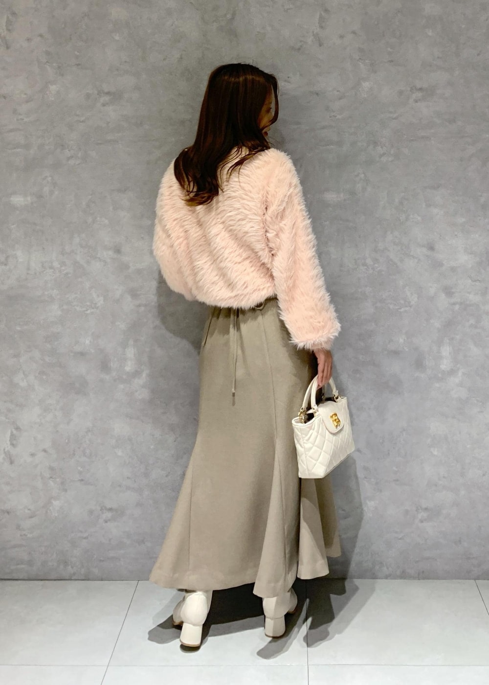 ホワイト系のブーツ、ベージュ系のスカート、ピンク系のカーディガン/ボレロを着用したレディースの冬コーディネートの6枚目の写真