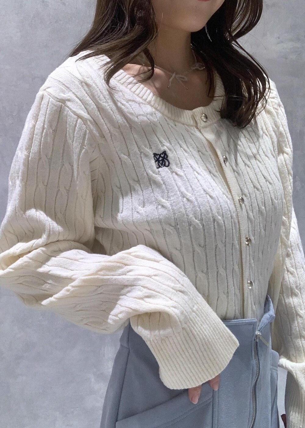 ホワイト系のハンドバッグ、ホワイト系のカーディガン/ボレロ、ブルー系のスカートを着用したレディースの冬コーディネートの8枚目の写真