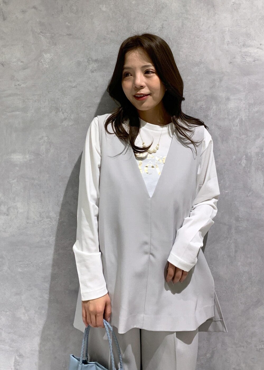 ブルー系のトートバッグ、ホワイト系のTシャツ/カットソー、ホワイト系のローファーを着用したレディースの冬コーディネートの6枚目の写真