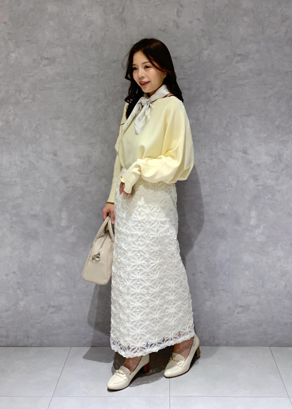 ホワイト系のスカート、ベージュ系のニット/セーター、ホワイト系のローファーを着用したレディースの冬コーディネートの3枚目の写真